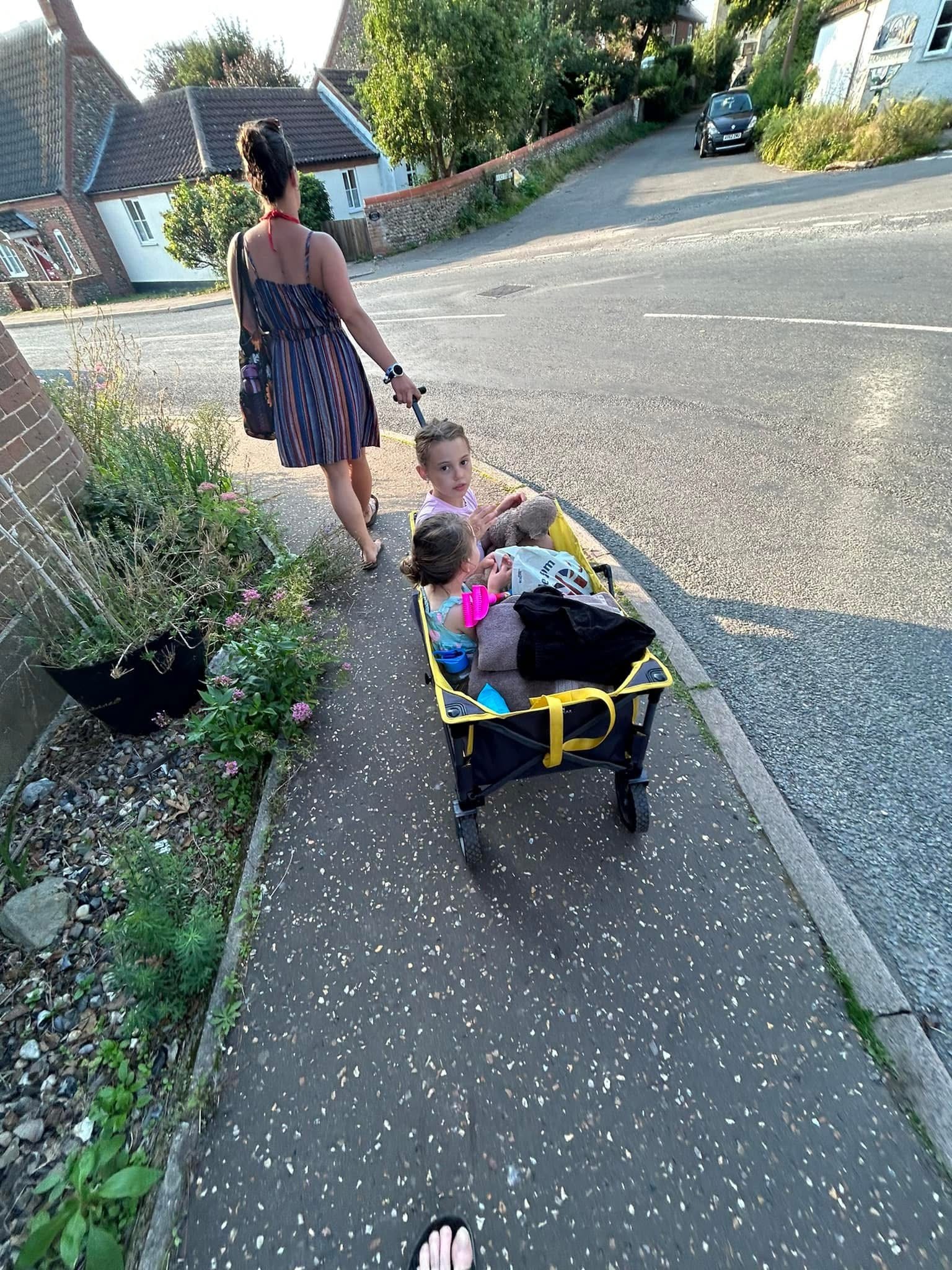 A Mum pulls her two daughters along in a wagon