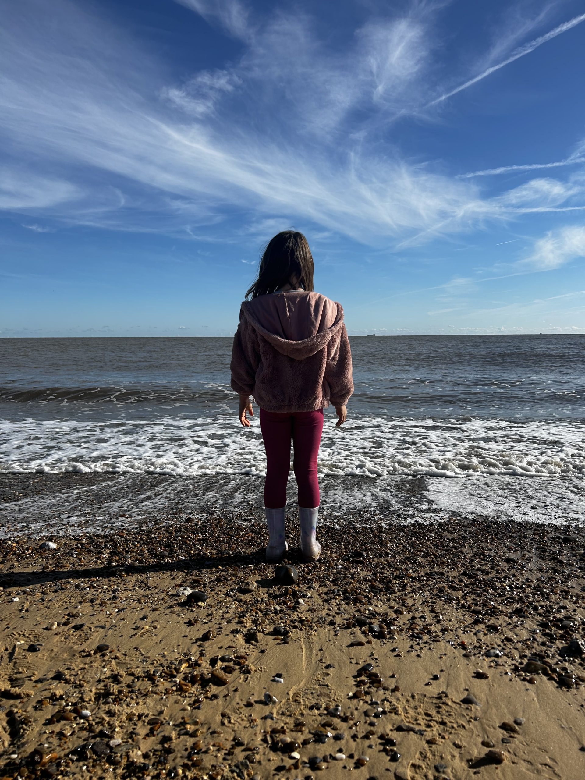 A girl stands on the beach by the sea in the UK